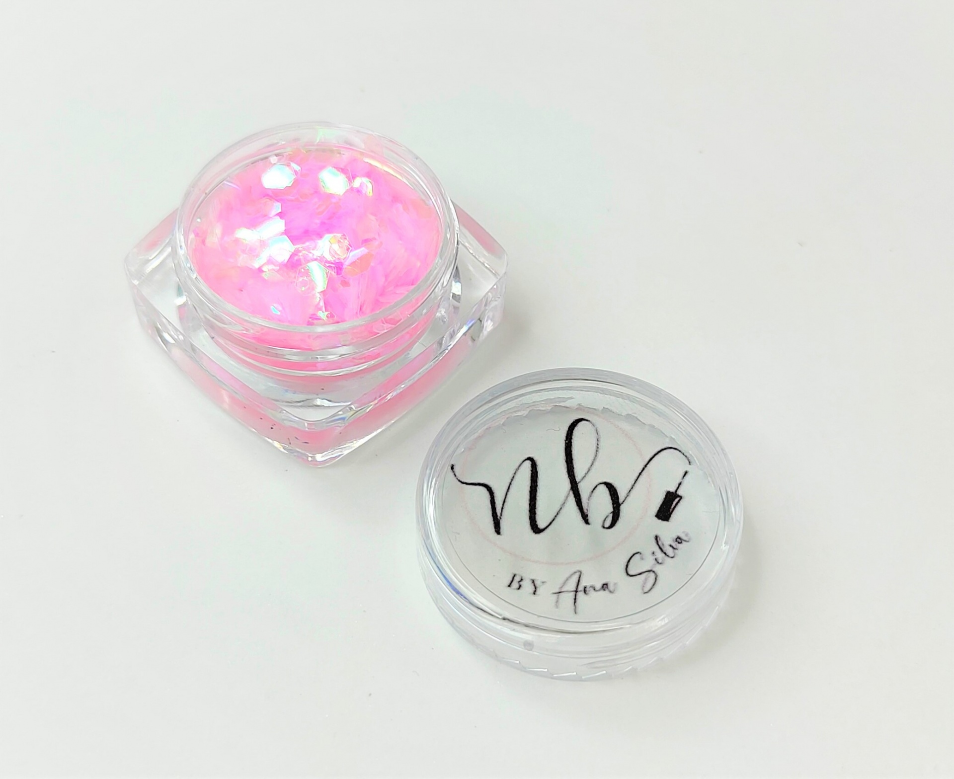 Frasco pequeno com purpurina rosa e tampa com texto preto