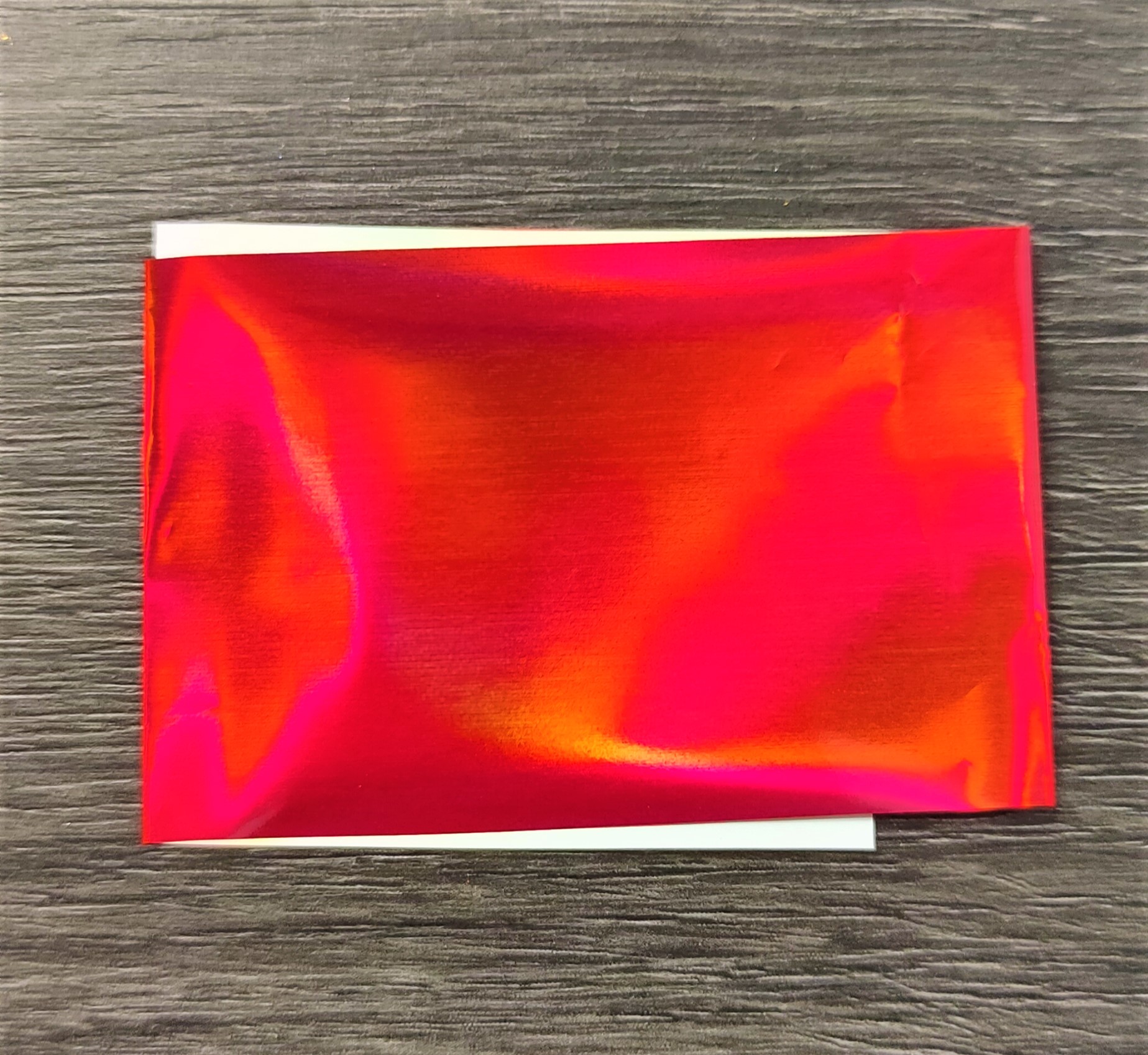 Envelope vermelho refletivo sobre superfície de madeira escura