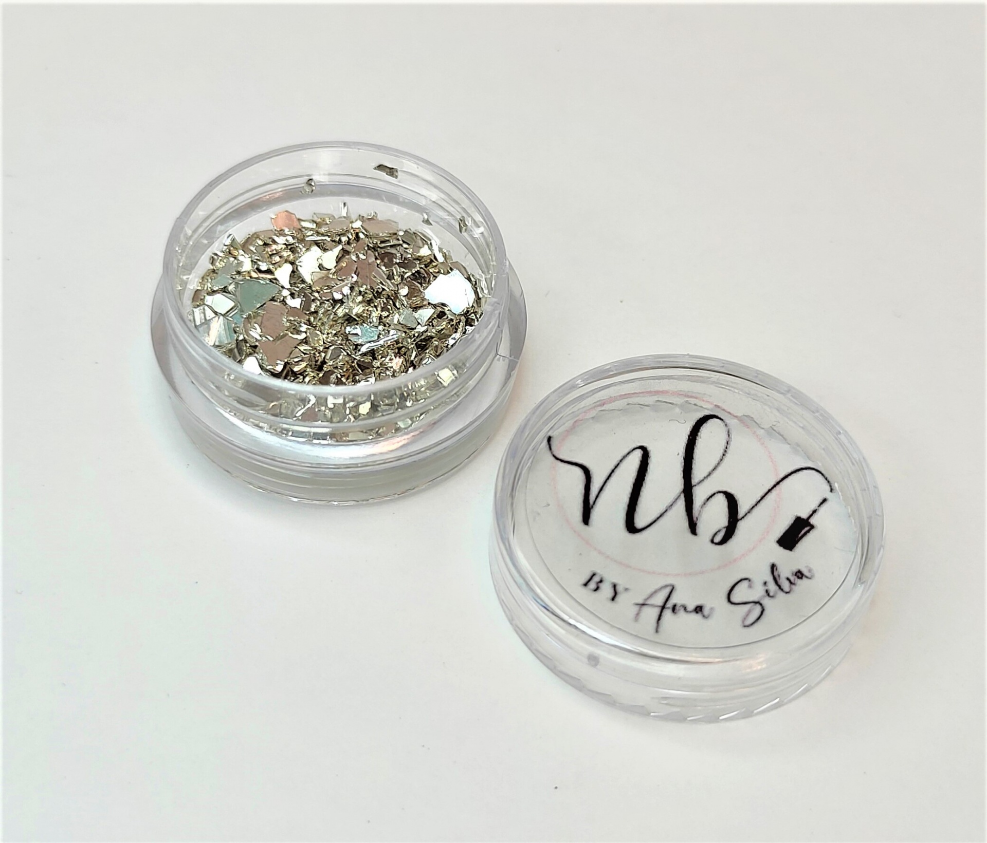 Pote de glitter prateado com tampa branca e texto preto