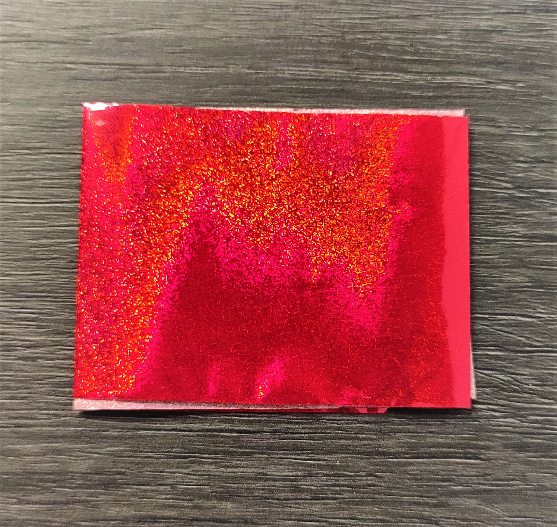Pacote pequeno com glitter vermelho em fundo de madeira escura