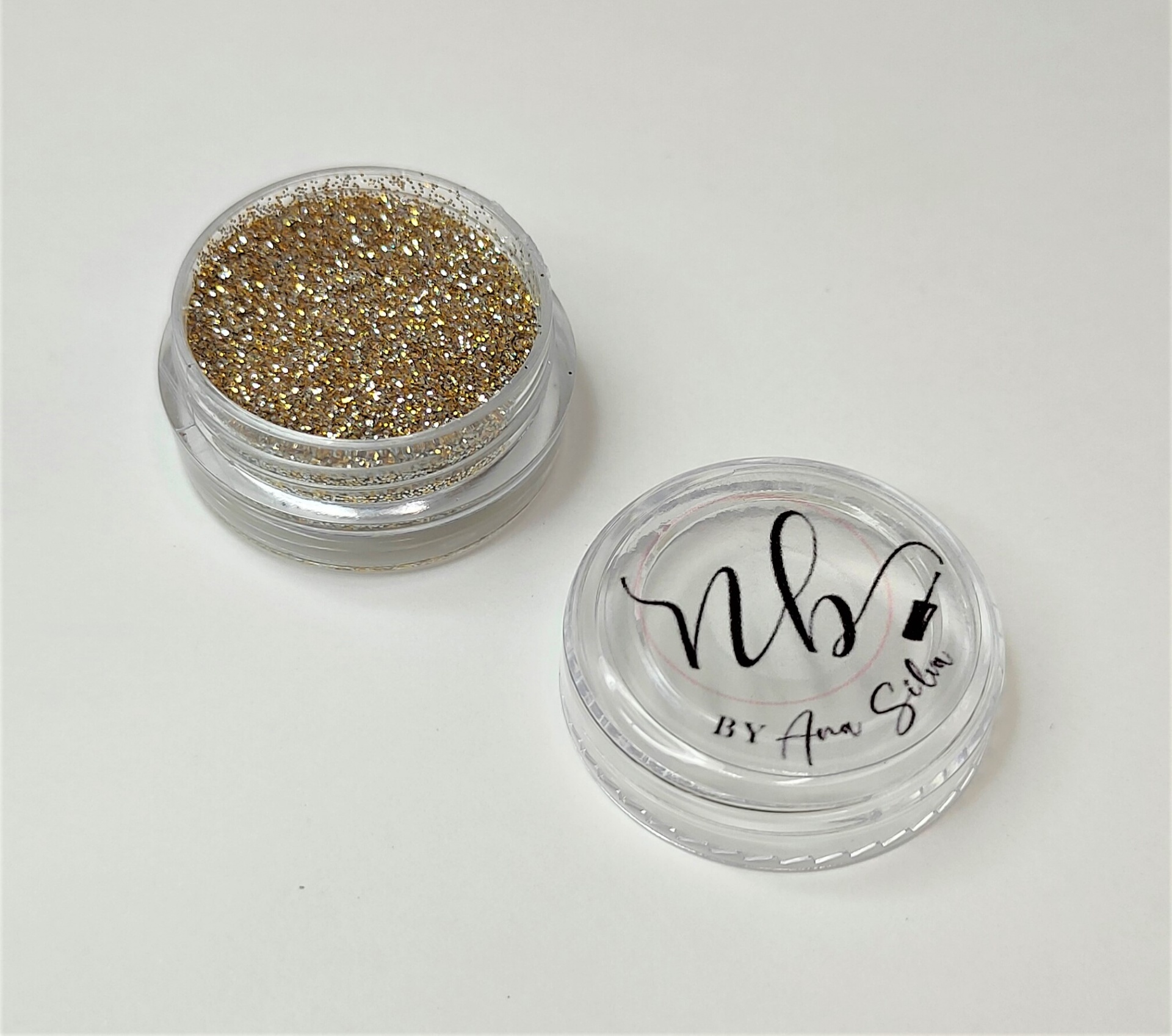 Pote transparente com glitter dourado e tampa com texto NB By Ana Silva