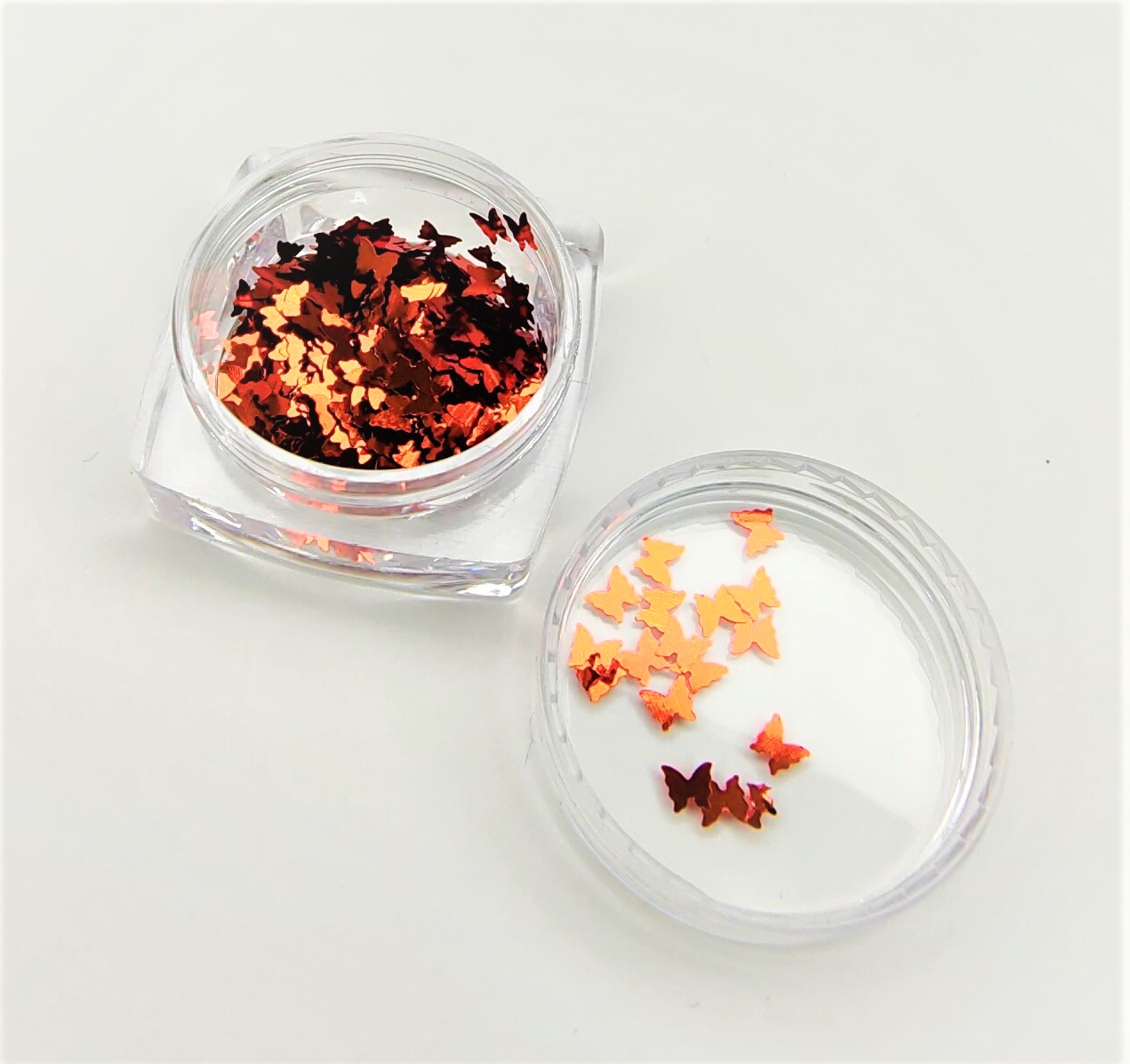 Frasco transparente com pequenas borboletas decorativas laranja e vermelhas