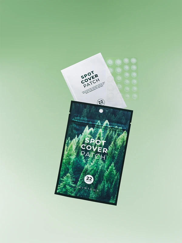 Embalagem verde com floresta e texto SPOT COVER PATCH com saqueta branca e patches transparentes.