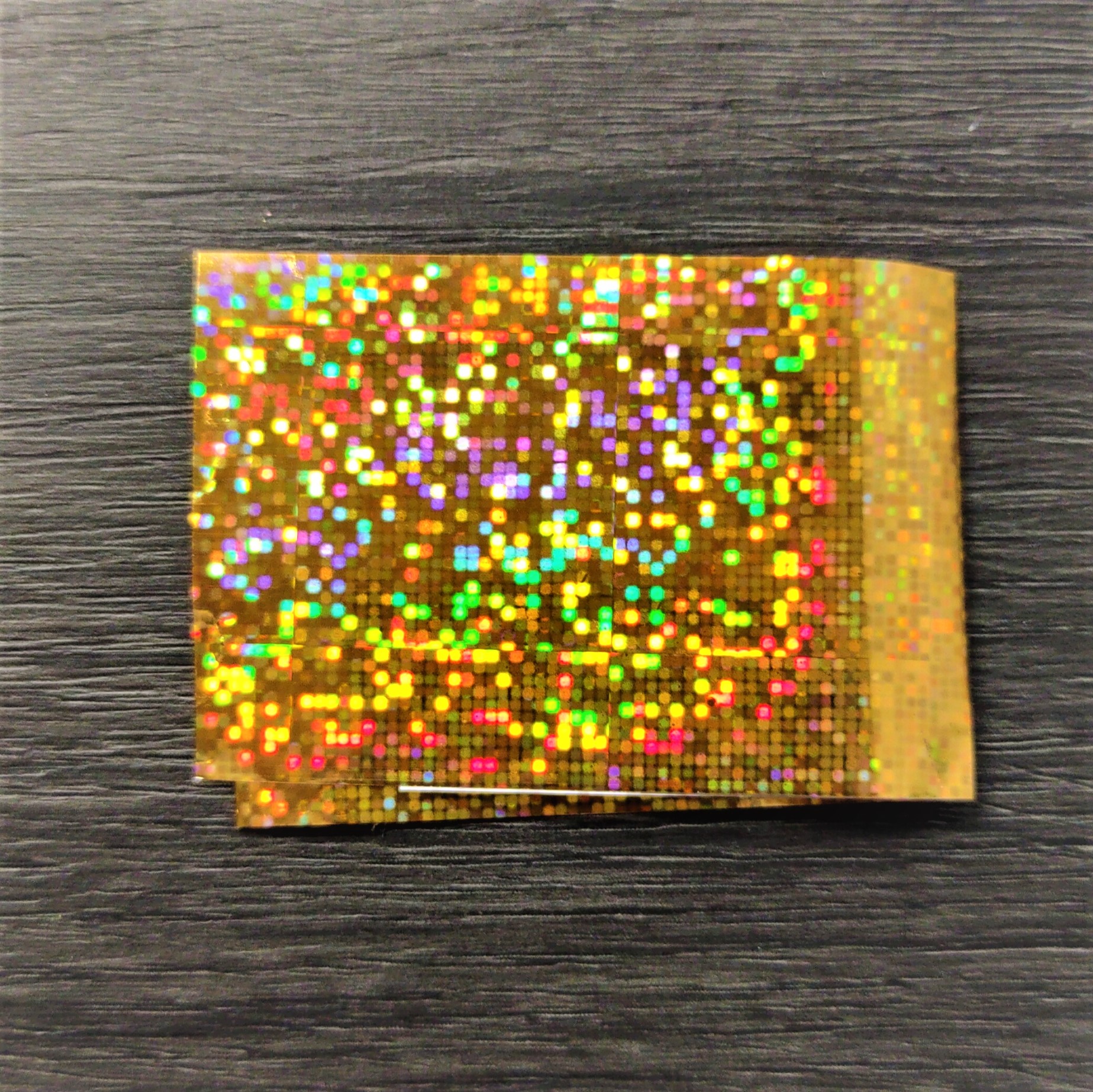 Pacote holográfico dourado sobre superfície escura