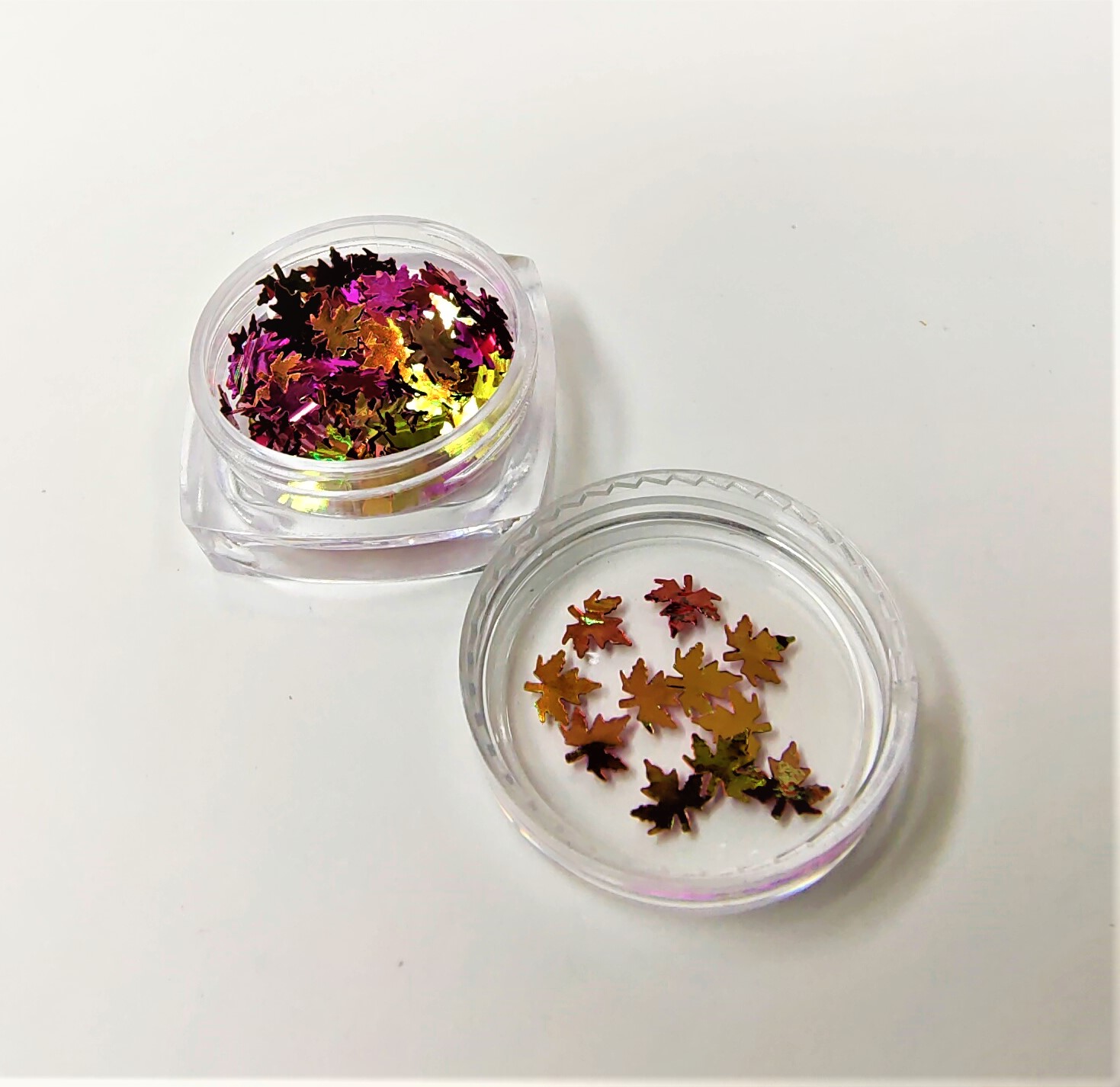 Confetes metálicos em forma de folhas de bordo dentro de recipientes transparentes