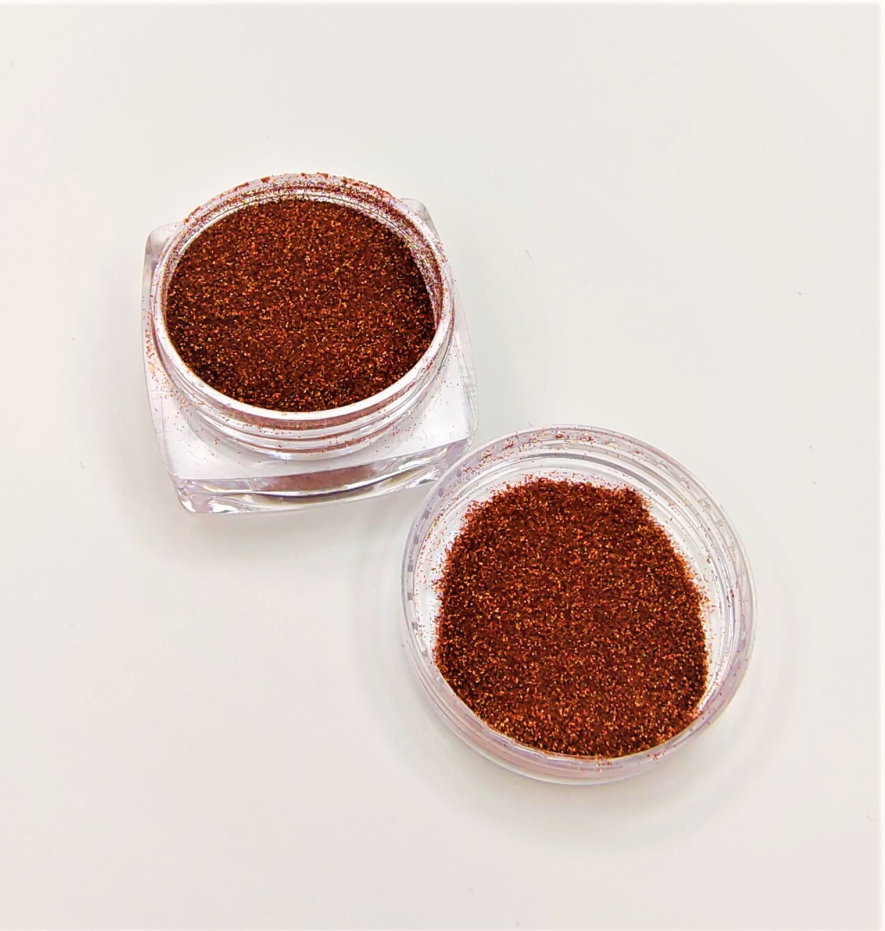 Pó de glitter castanho num frasco de plástico transparente com tampa ao lado