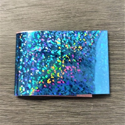 Folha autocolante holográfica azul com padrão brilhante sobre madeira cinzenta