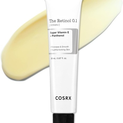 Tubo branco de creme The Retinol 0.1 da COSRX com creme amarelo-bege ao fundo