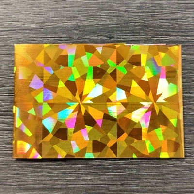 Cartão holográfico dourado com padrão facetado sobre madeira escura