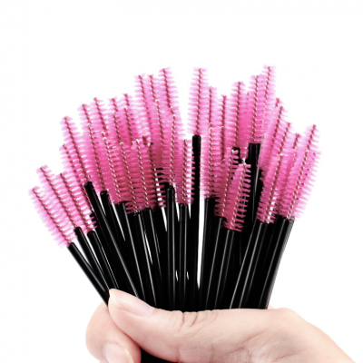 Aplicadores para rímel rosa com cabo preto segurados na mão