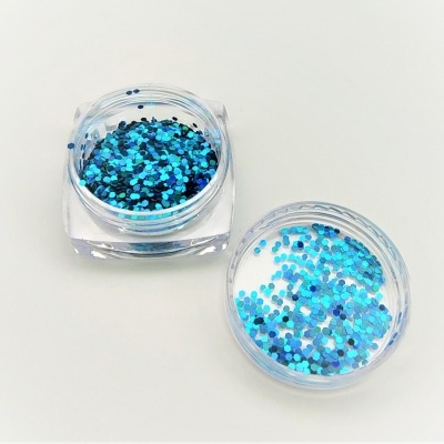 Pote transparente com glitter azul e tampa ao lado sobre fundo branco