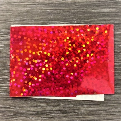 pacote pequeno holográfico vermelho sobre madeira cinzenta