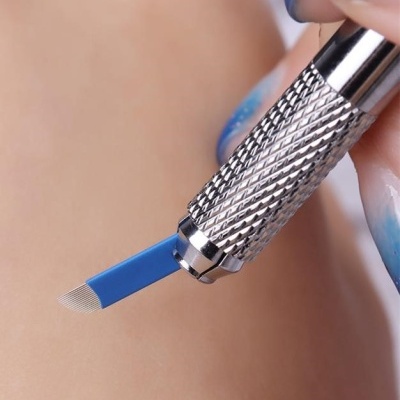 Ferramenta metálica com lâmina azul de cerdas finas segurada por mão com unhas decoradas