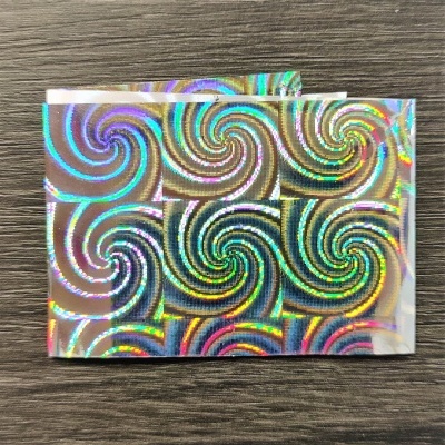 Folha holográfica com padrão de redemoinhos coloridos sobre madeira escura