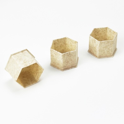 Três recipientes hexagonais bege com textura sobre fundo branco