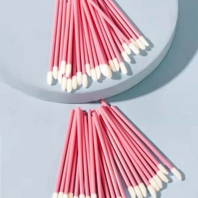 Aplicadores de maquilhagem rosa com pontas brancas sobre superfície clara