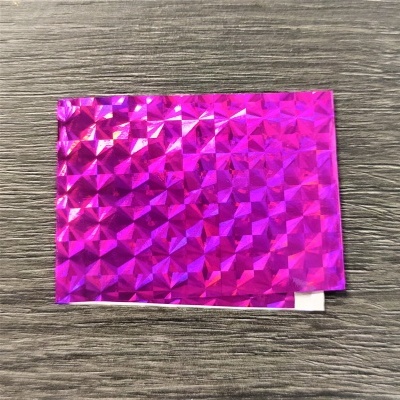 Fólios decorativos holográficos rosa com padrão geométrico sobre madeira cinza