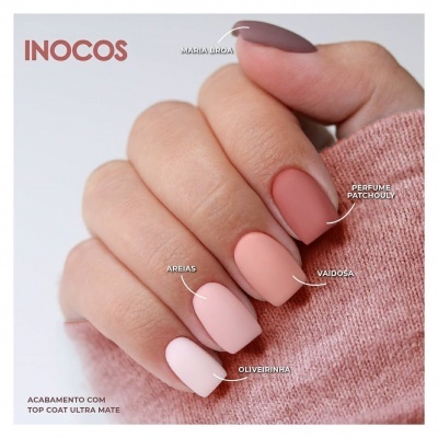 Mão feminina com unhas pintadas em tons nude e rosa com nomes das cores