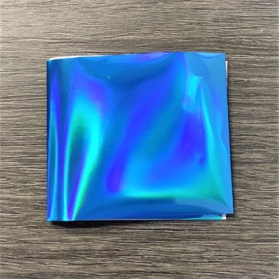 Folha metálica azul iridescente sobre superfície de madeira escura