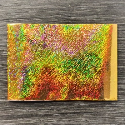 Cartão holográfico colorido sobre superfície de madeira cinza escuro.