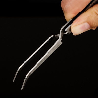Pinça metálica com ponta arredondada sendo segurada por uma mão