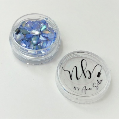 Frasco transparente com pedaços de concha azul e tampa com texto 'nb BY Ana Silva'.