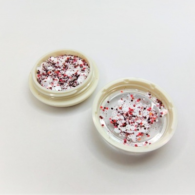 Frasco aberto com glitter colorido em superfície branca