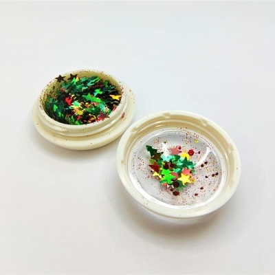 Frasco pequeno aberto com glitter em forma de estrelas coloridas