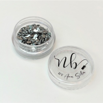 Embalagem transparente com pequenas peças prateadas e texto 'nbv By Ana Silva'