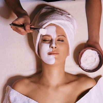 Mulher a receber aplicação de máscara facial branca num SPA