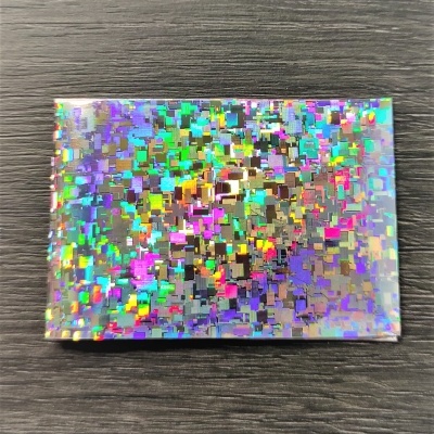 Caixa pequena com padrão holográfico colorido sobre madeira escura