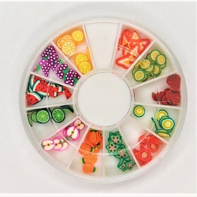 Caixa redonda com divisórias contendo enfeites em polímero coloridos em forma de fatias de frutas e legumes.