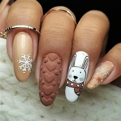 Unhas decoradas com padrão de corações, flocos de neve e coelho sobre fundo neutro.