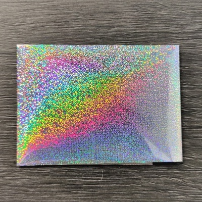 Caixa holográfica prateada com reflexos coloridos sobre madeira escura