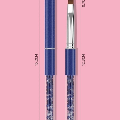 Pincel de cerdas marrons com cabo azul escuro e parte inferior transparente com pedras azuis sobre fundo rosa