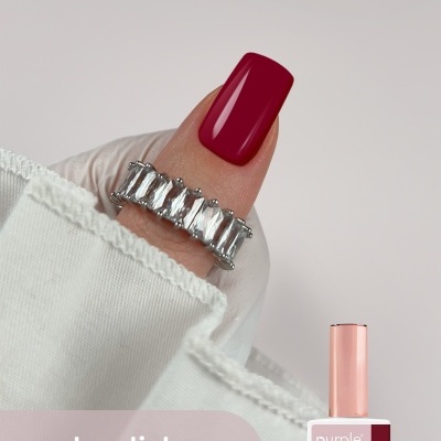 Unha com verniz gel vermelho escuro e anel prateado, ao lado embalagem de gel polish Purple Professional 024 romance.