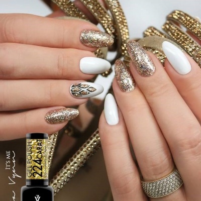 Unhas com verniz gel branco e dourado brilhante com anel de pedras e decoração dourada ao fundo