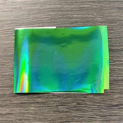 Folha holográfica verde sobre madeira castanha