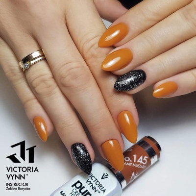 Mãos com unhas pintadas de laranja e preto brilhante, anel dourado, garrafa de verniz sobre superfície branca