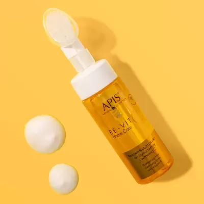 Frasco amarelo de produto cosmético APIS Re-Vit Home Care com creme ao lado sobre fundo amarelo