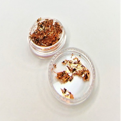 Contêiner transparente com flocos metálicos dourados em superfície branca