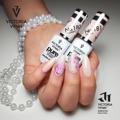 Unhas decoradas com verniz Victoria Vynn e flores, com frascos de verniz e pérolas ao fundo