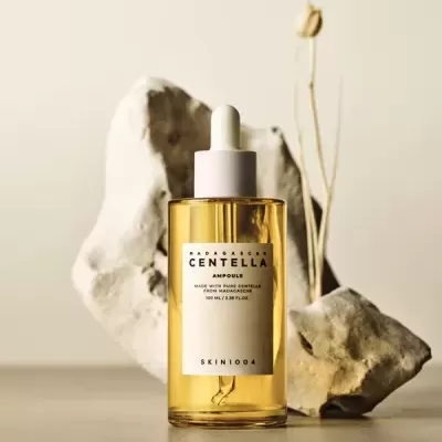 frasco de sérum amarelo com conta-gotas branco e rótulo branco em fundo com pedras