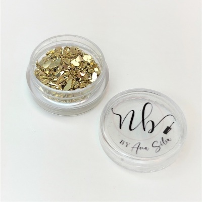 Frasco transparente com flocos dourados e tampa com texto 'nb BY Ana Silva'
