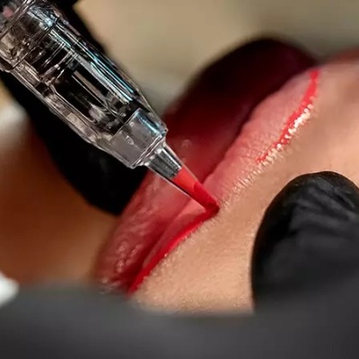 Tatuagem labial a vermelho em lábios com máquina de micropigmentação.