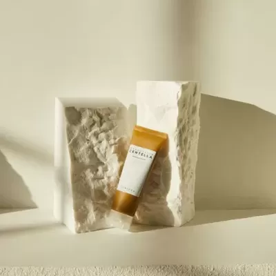 Frasco âmbar de gel com rótulo branco entre duas pedras brancas