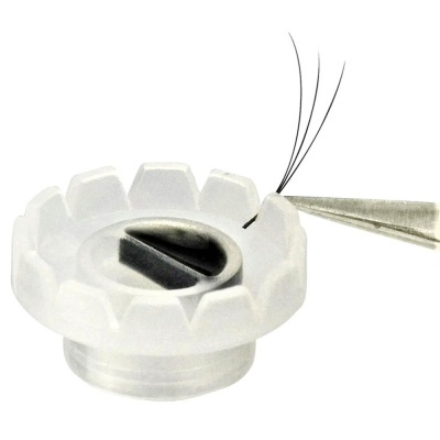 Suporte plástico branco com fenda preta e pêlos presos por pinça metálica