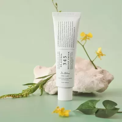 Tubo branco de creme Dalthea 345 Relief Cream com flores amarelas e pedra branca em fundo verde claro