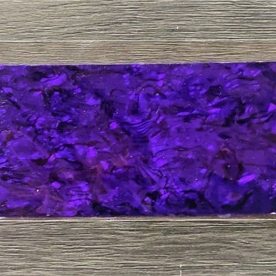 Placa retangular com padrão marmoreado roxo sobre superfície de madeira cinzenta