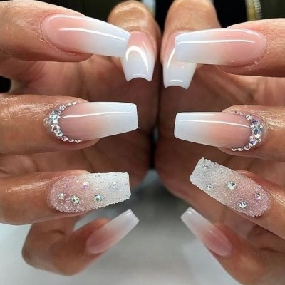 Unhas compridas com gradiente branco para rosa, pedrarias e textura rugosa